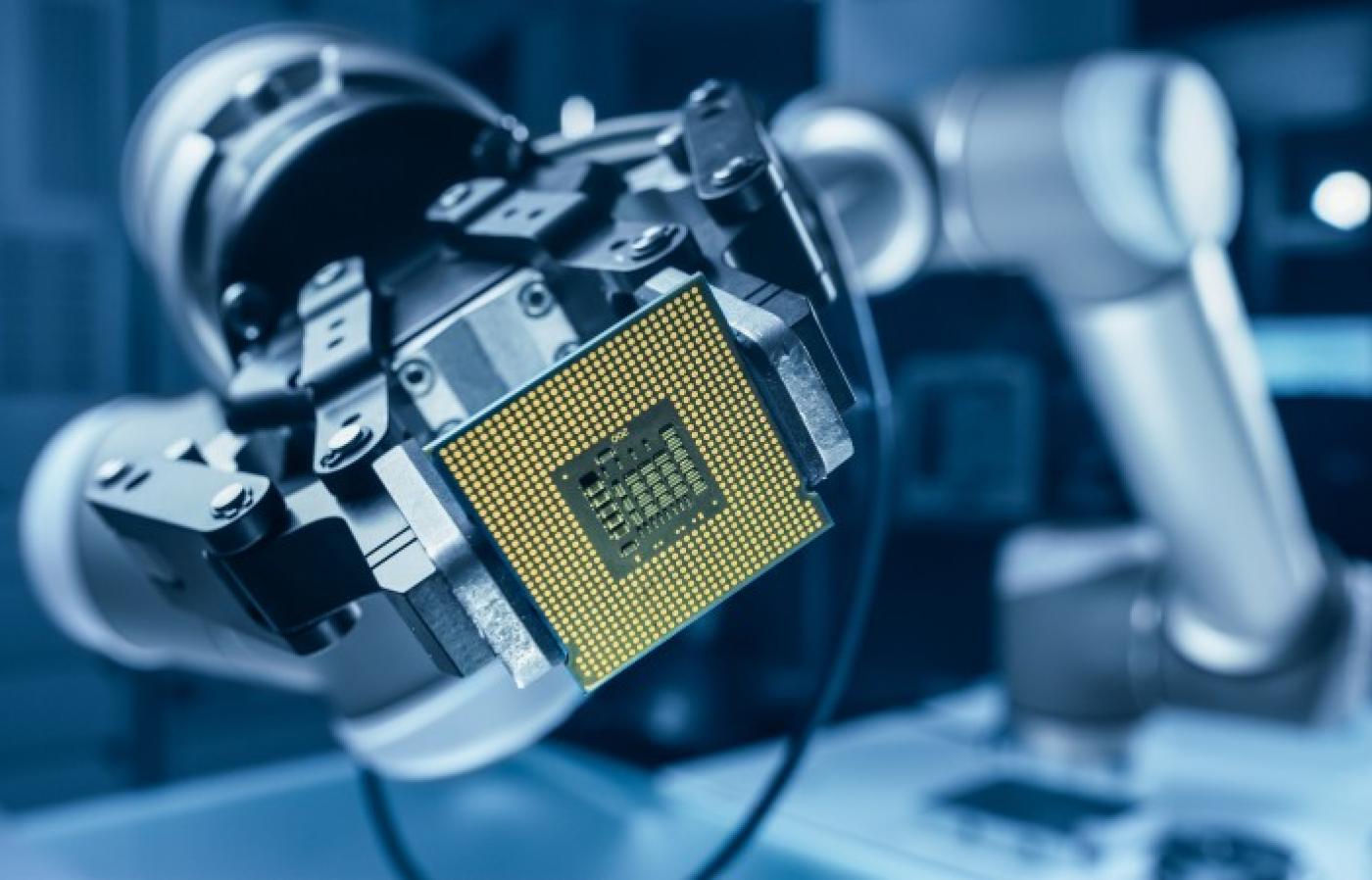Robot arm holding a computer processor chip.
